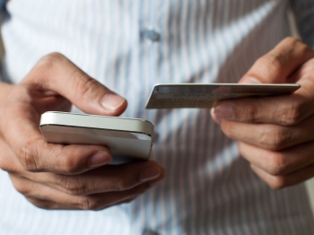 Man looking at phone and credit card